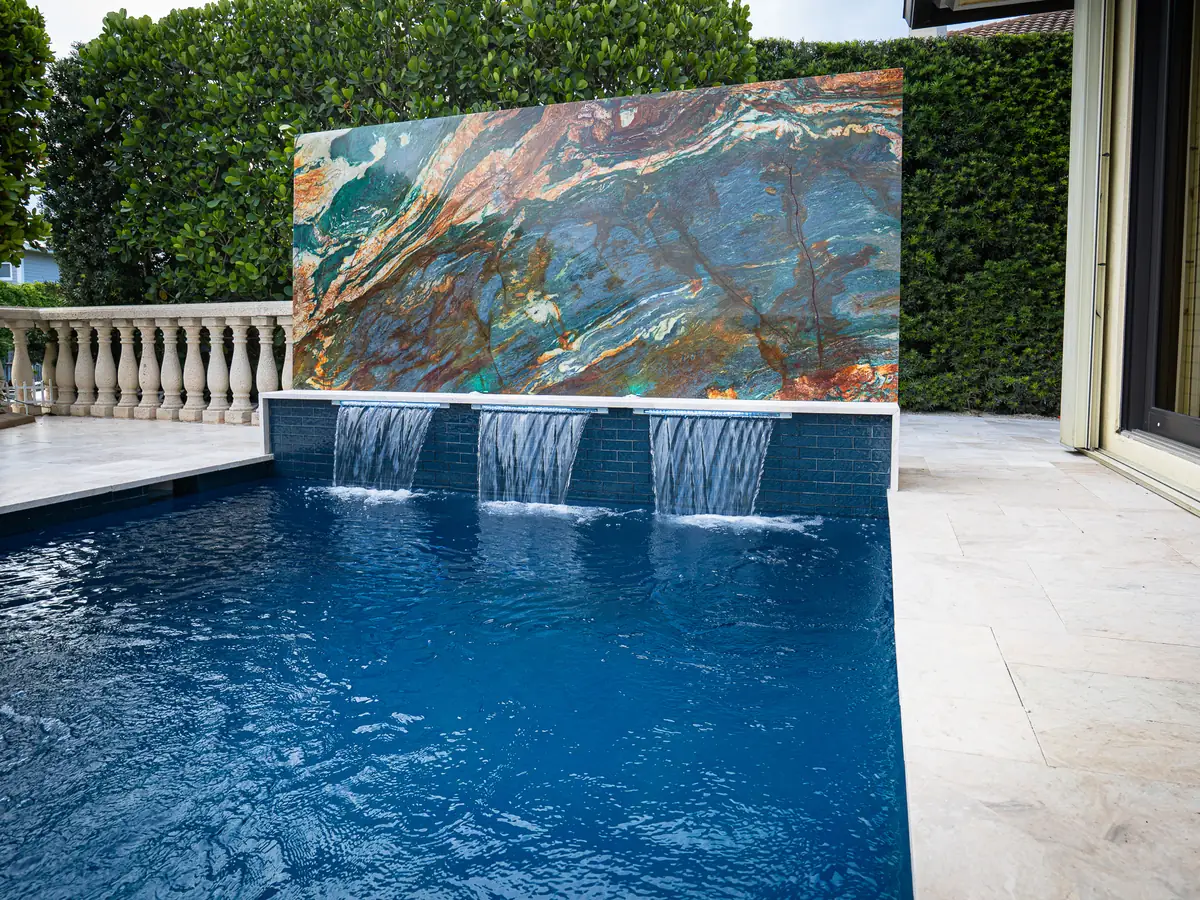 Renovated pool in Delray Beach with a quartz-clad raised wall and three sheer descent waterfalls
