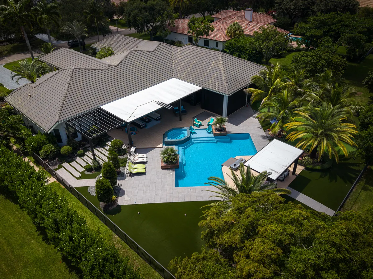 Aerial view of a renovated backyard pool with covered lanai and lounge seating in Parkland, FL